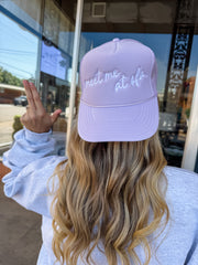 Person wearing a lavender cap with text, standing outside a building.