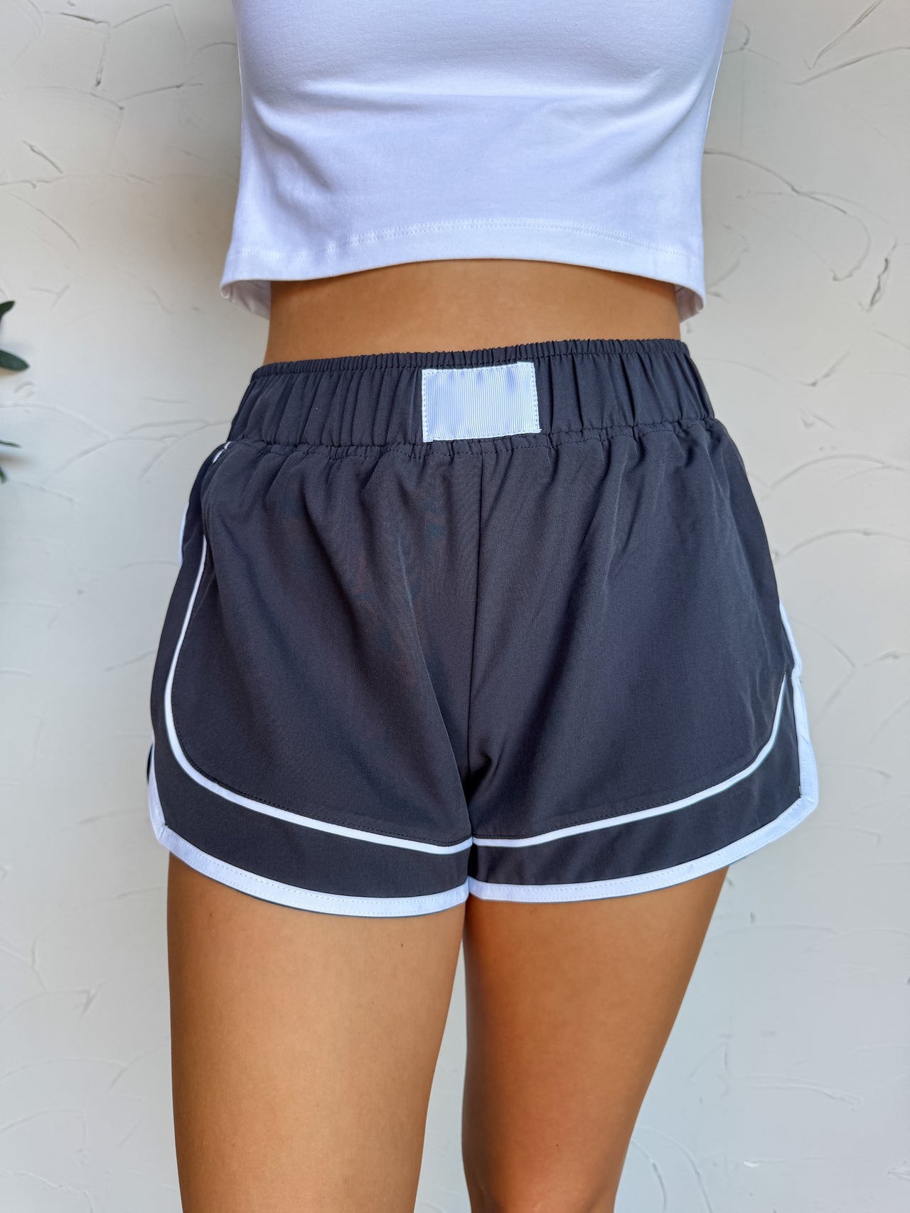 Person wearing navy shorts with white trim against a light background