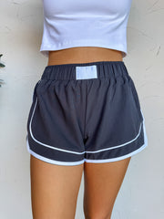 Person wearing navy shorts with white trim against a light background