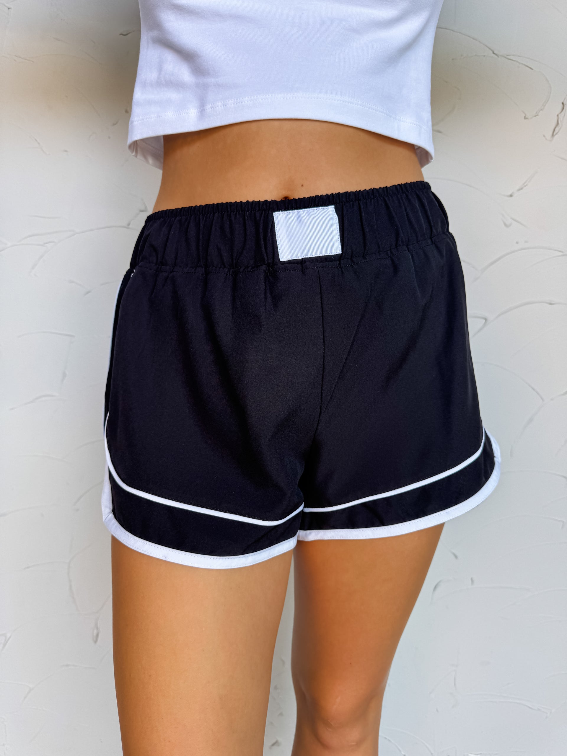 Girl in black shorts in font of plain wall 