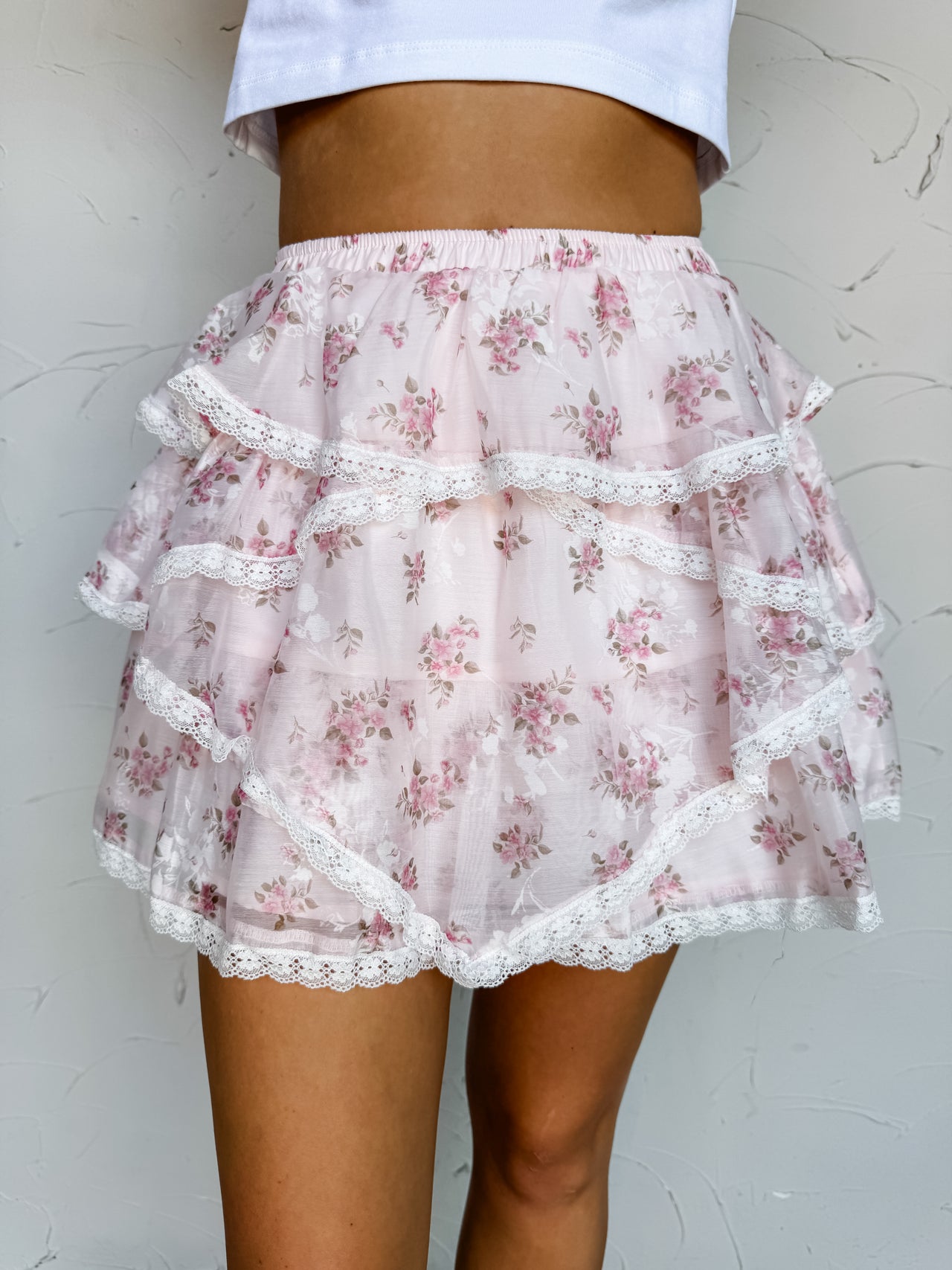 Floral tiered skirt with lace trim worn by a person against a plain background