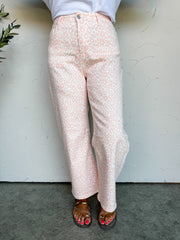 Person wearing light pink leopard pants against a white wall.