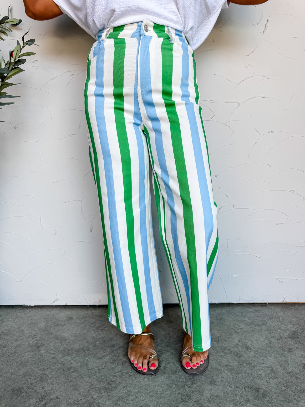 Girl in stripe pants in front of plain wall 