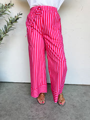 Person wearing pink and white striped pants against a plain background