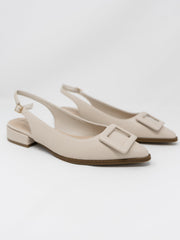 A pair of Pierre Dumas cream-colored pointed-toe slingback flats displayed against a solid white background. The shoes feature an adjustable ankle strap with a small gold buckle, a very low block heel, and a large matching cream square buckle detail across the pointed toe.