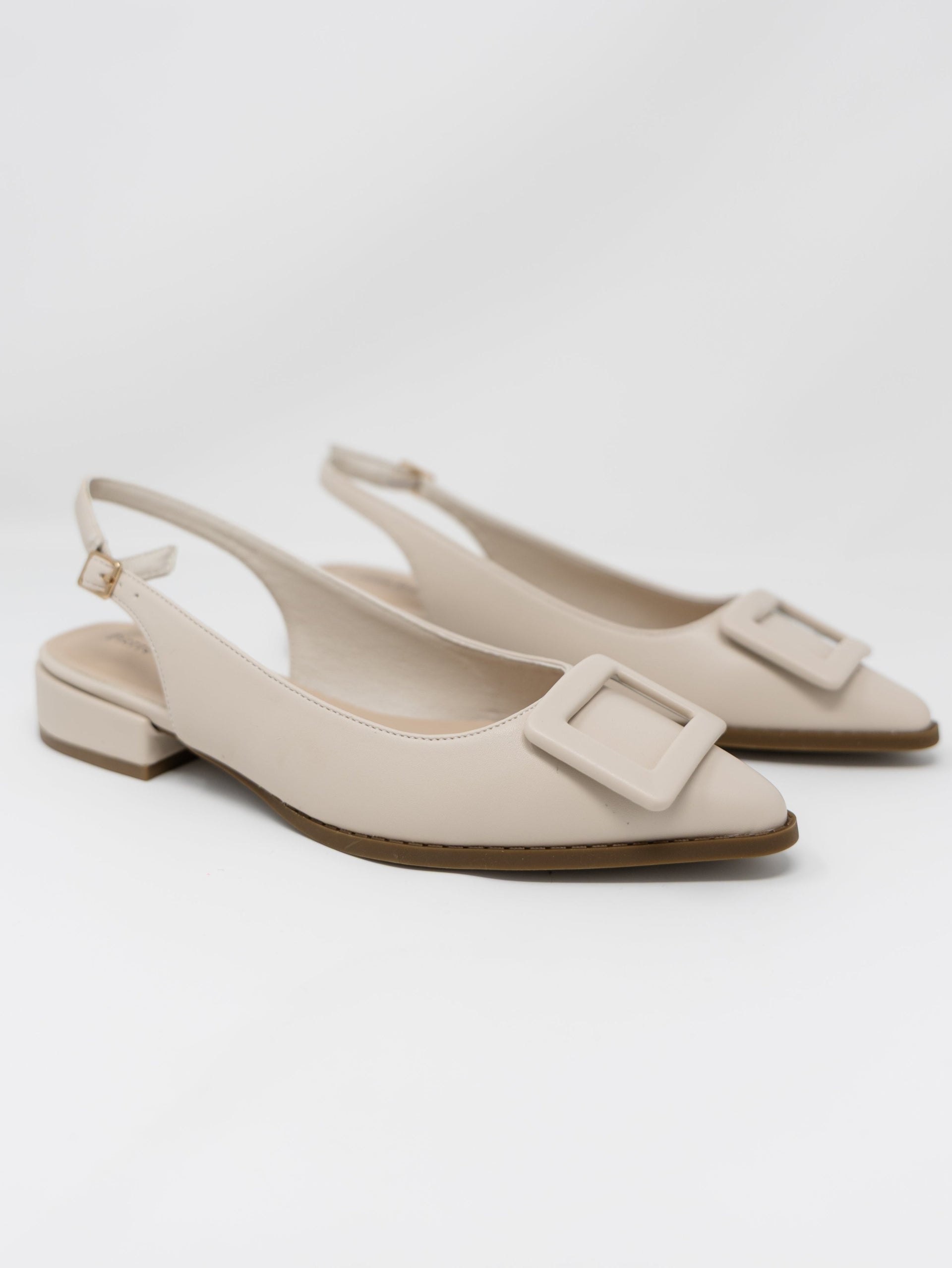 A pair of Pierre Dumas cream-colored pointed-toe slingback flats displayed against a solid white background. The shoes feature an adjustable ankle strap with a small gold buckle, a very low block heel, and a large matching cream square buckle detail across the pointed toe.
