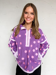 Purple pullover with pink polka dots, light lavender contrast trim, a partial-zip stand collar, long sleeves, and front pockets, made of 65% polyester and 35% cotton.