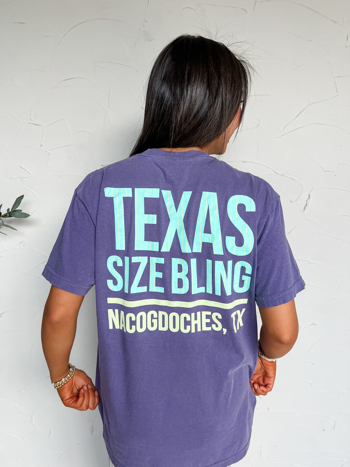 Grape-purple Comfort Colors tee made of 100% garment-dyed cotton, with a small “TSB Boutique” front screenprint and large “Texas Size Bling, Nacogdoches, TX” back screenprint in aqua and pale yellow.