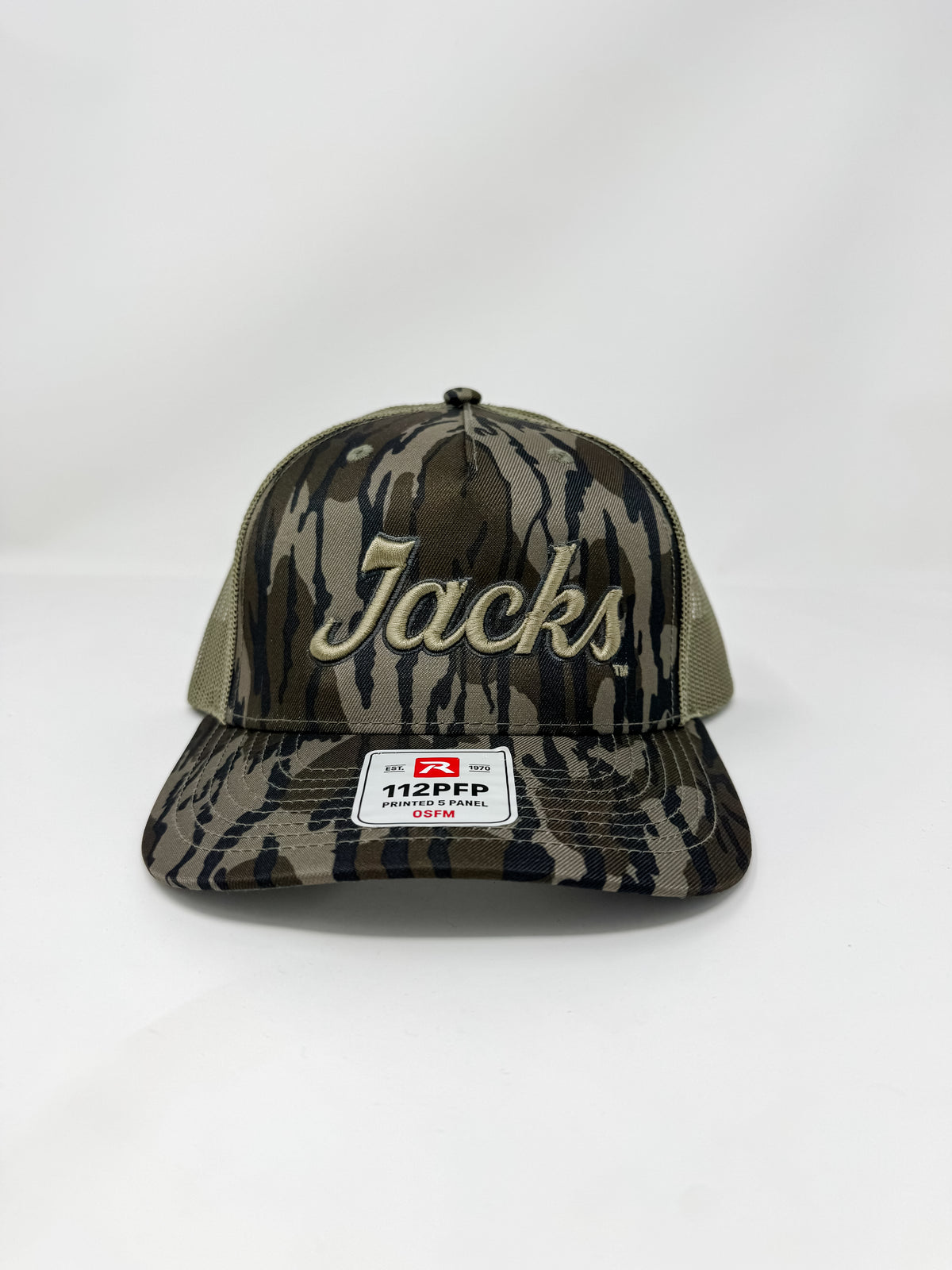 A Richardson 112PFP timber camo trucker hat embroidered with "Jacks" in raised 3D beige script thread, featuring tan mesh back panels, displayed against a solid white background.