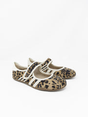 A pair of leopard print Mary Jane style flats with off-white trim and athletic stripes on the sides, set against a plain white background. The shoes feature an adjustable hook-and-loop strap across the top and a thin, flexible low-profile sole.