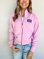 Pink French terry full-zip jacket by G Ink with a stand collar, long sleeves, banded cuffs and hem, and a purple chest patch featuring three rows of white SFASU lettering.