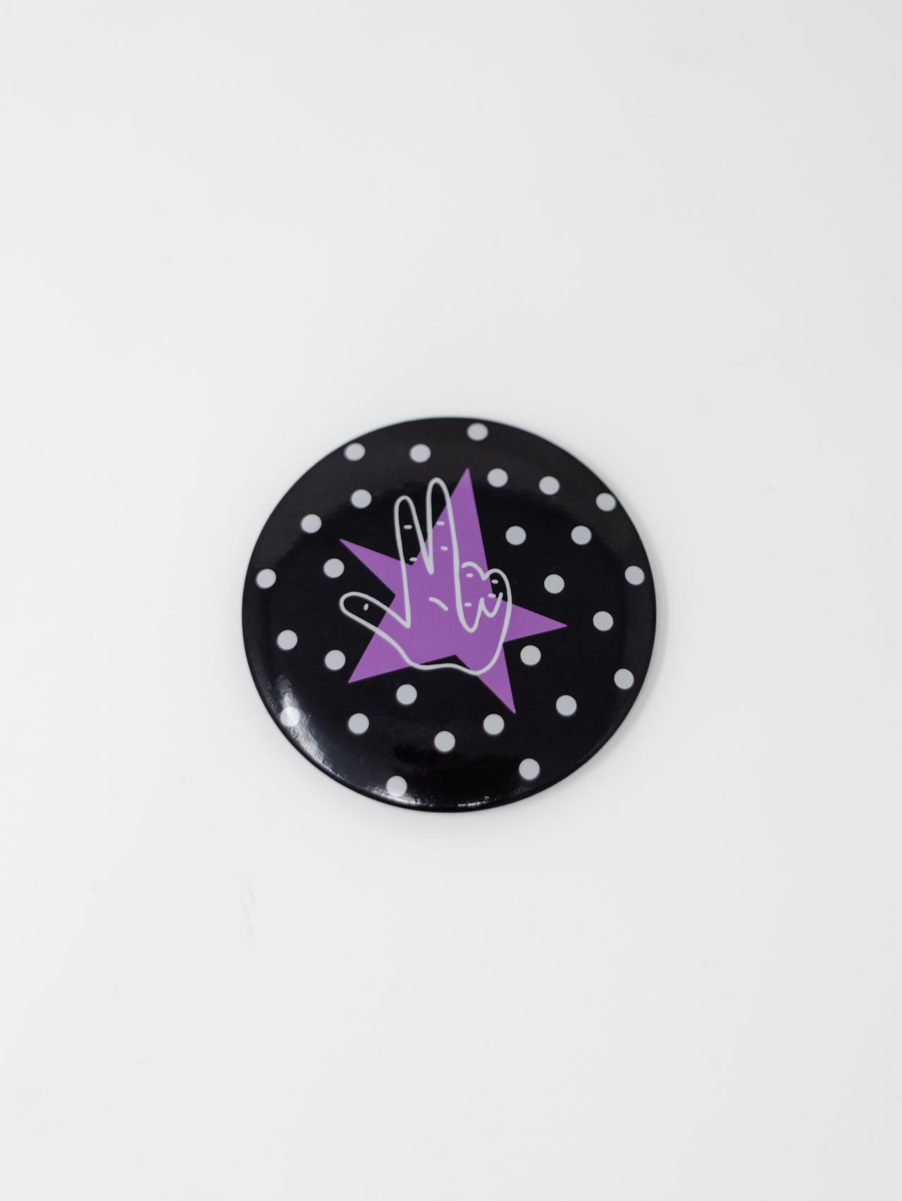 A round pin button featuring a black background with white polka dots, centered with a purple star and a white-outlined "Axe 'Em" hand gesture, displayed against a plain white background.