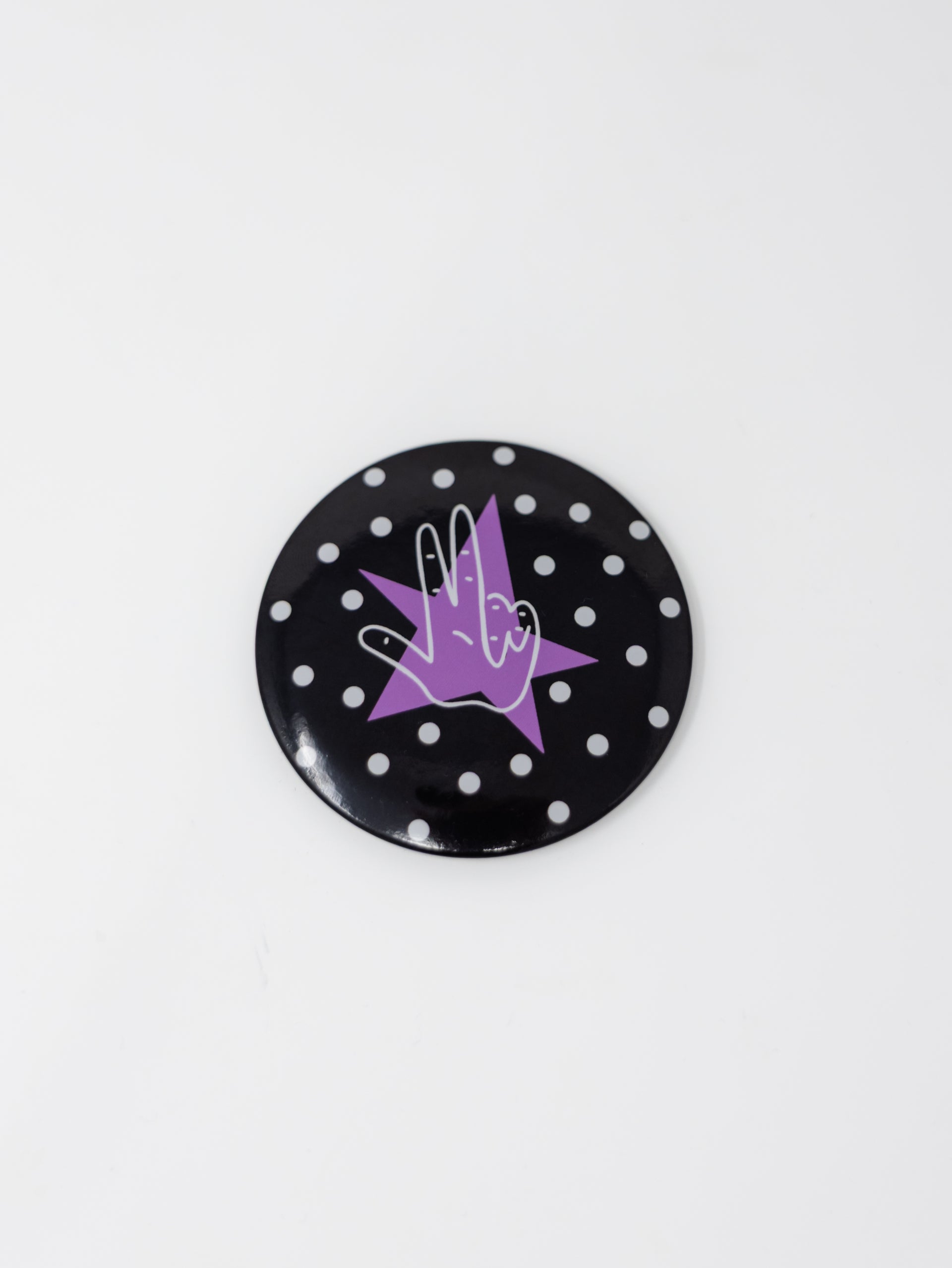 A round pin button featuring a black background with white polka dots, centered with a purple star and a white-outlined "Axe 'Em" hand gesture, displayed against a plain white background.