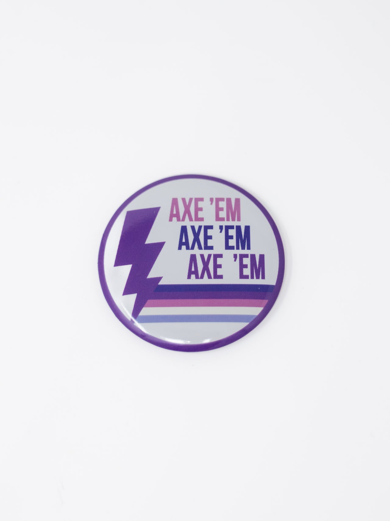 A round pin button featuring a white background with a purple outer border, a purple lightning bolt on the left side, and "AXE 'EM" stacked three times in pink, navy, and purple, grounded by multi-colored horizontal stripes along the bottom.