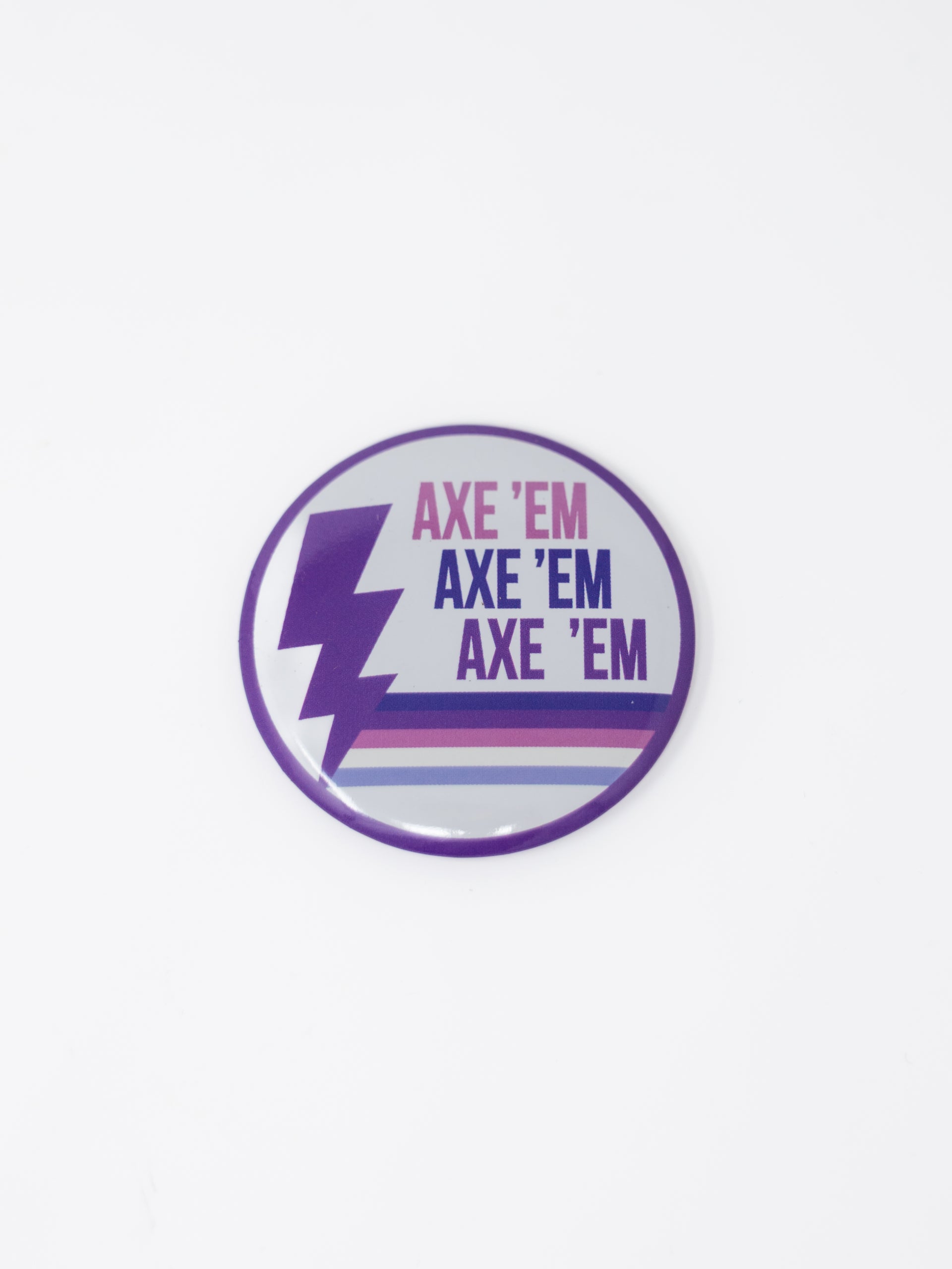 A round pin button featuring a white background with a purple outer border, a purple lightning bolt on the left side, and "AXE 'EM" stacked three times in pink, navy, and purple, grounded by multi-colored horizontal stripes along the bottom.