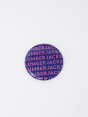 A round button badge featuring a purple and pink repeating pattern of the brand name 'LUMBERJACKS' on a plain white background.