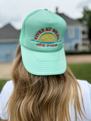 Person wearing a light blue cap with text, outdoors.