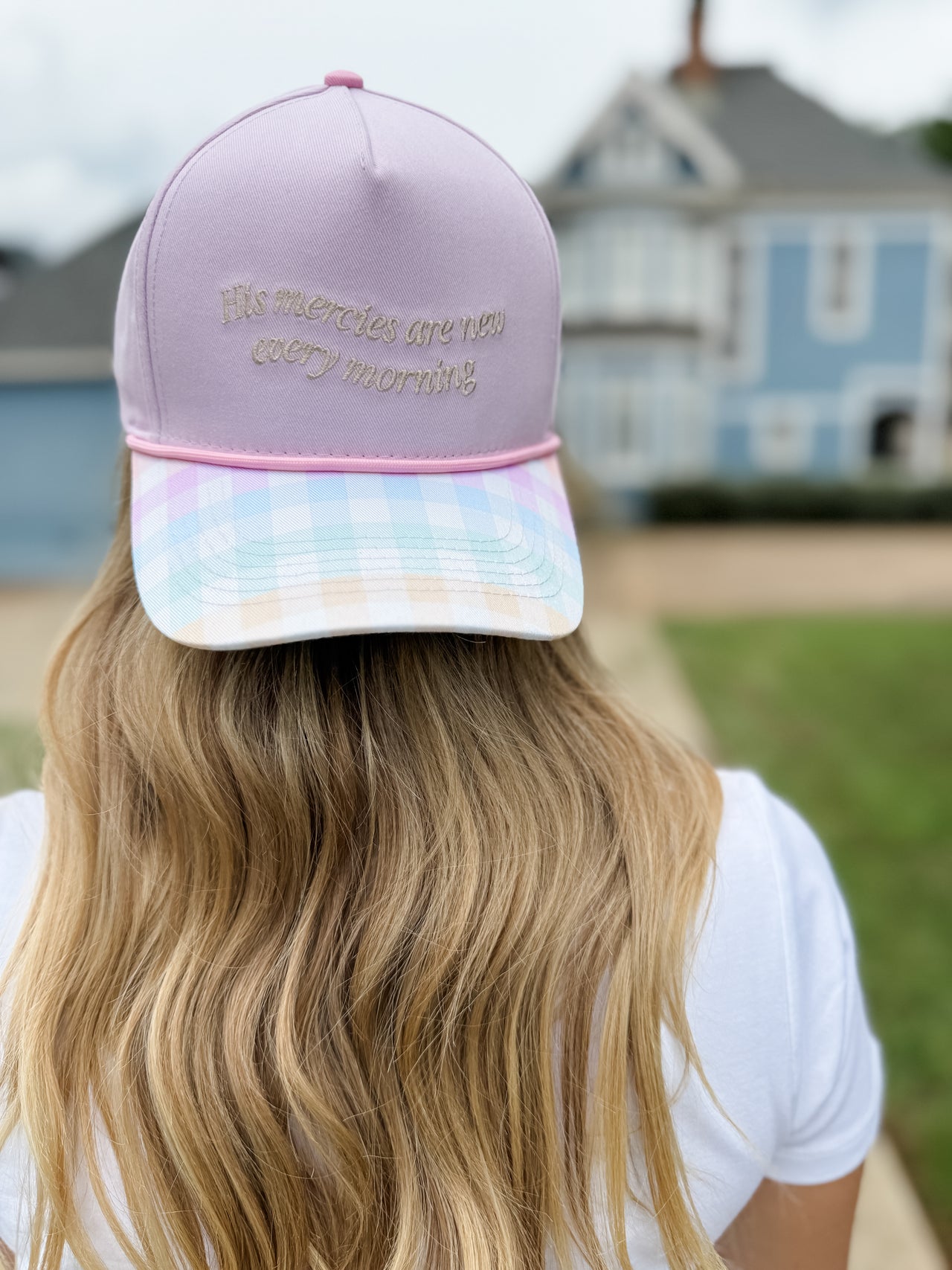 Person wearing a pink and white cap with text, standing outdoors.