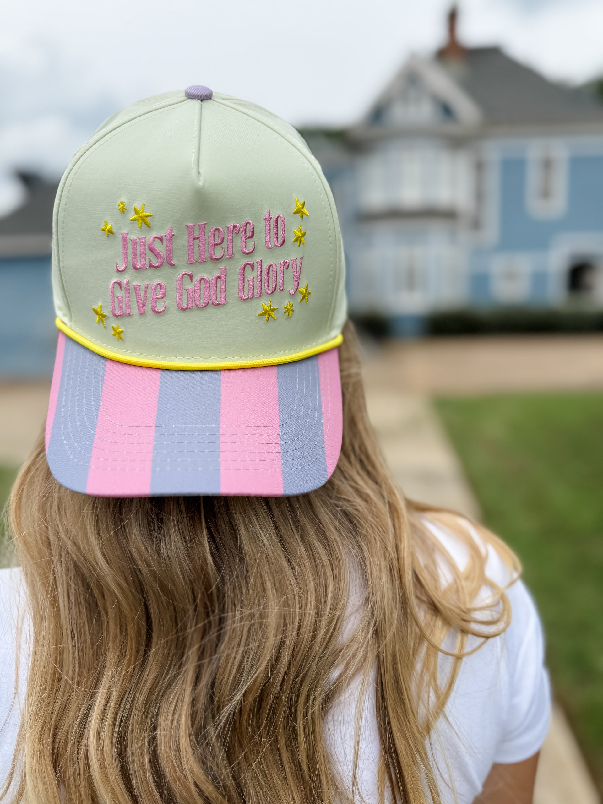 Person wearing a cap with text and colorful design, standing outdoors.
