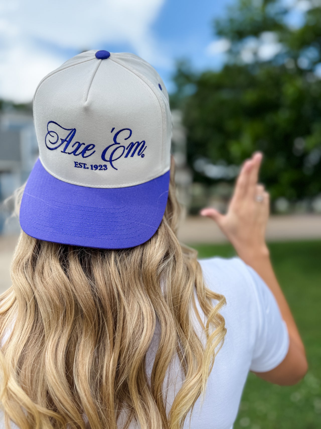 Person wearing a gray and purple cap with 'Axe Em' branding outdoors.