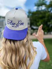 Person wearing a gray and purple cap with 'Axe Em' branding outdoors.