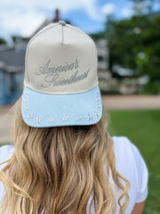 Person wearing a cap with 'America's Sweetheart' text and star details outdoors.
