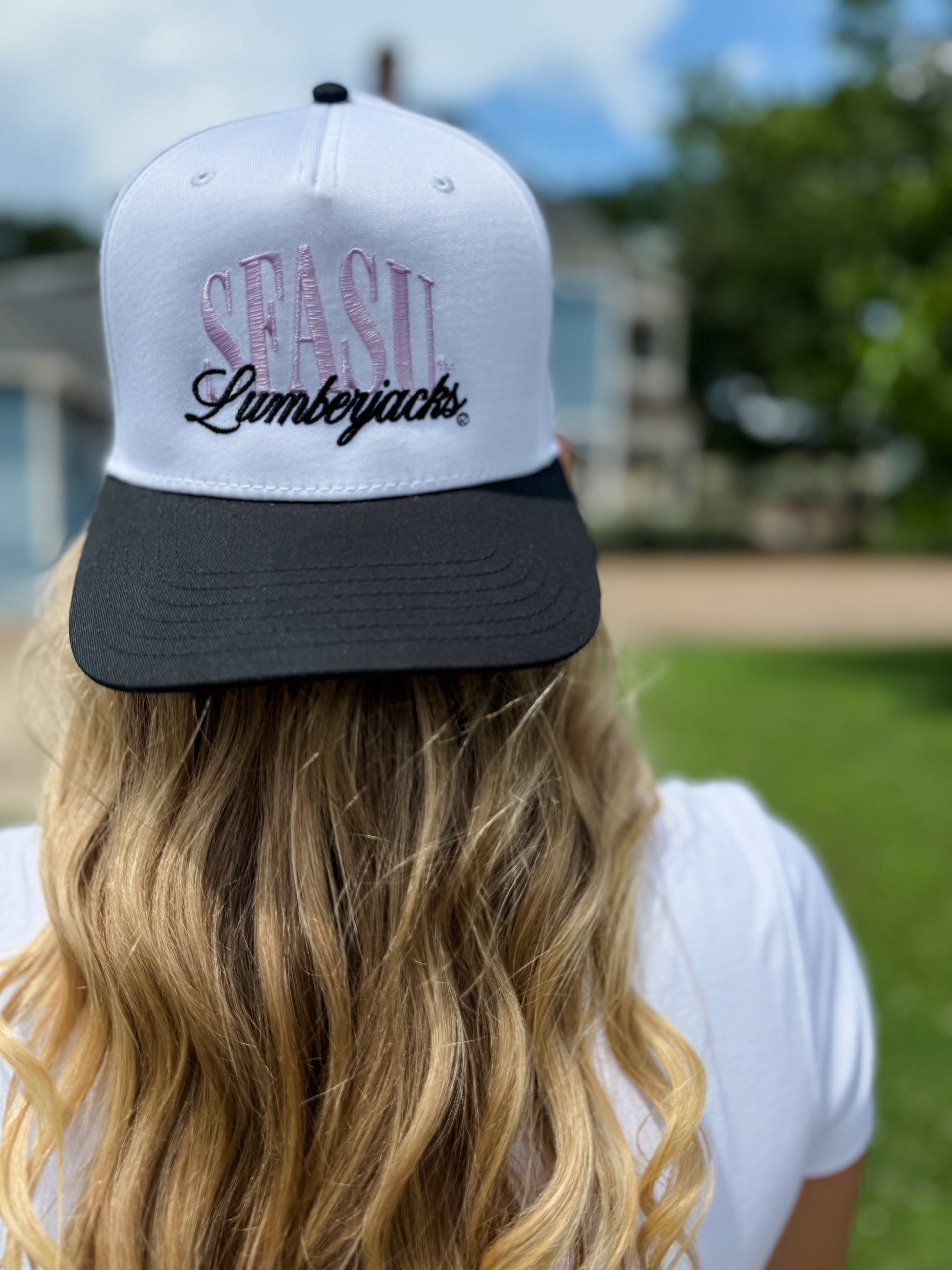 Person wearing a white and black cap with 'SEASU Lumberjacks' text, outdoors.