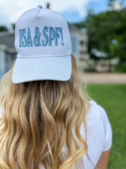 Person wearing a light blue cap with 'USA & SPF!' text outdoors.