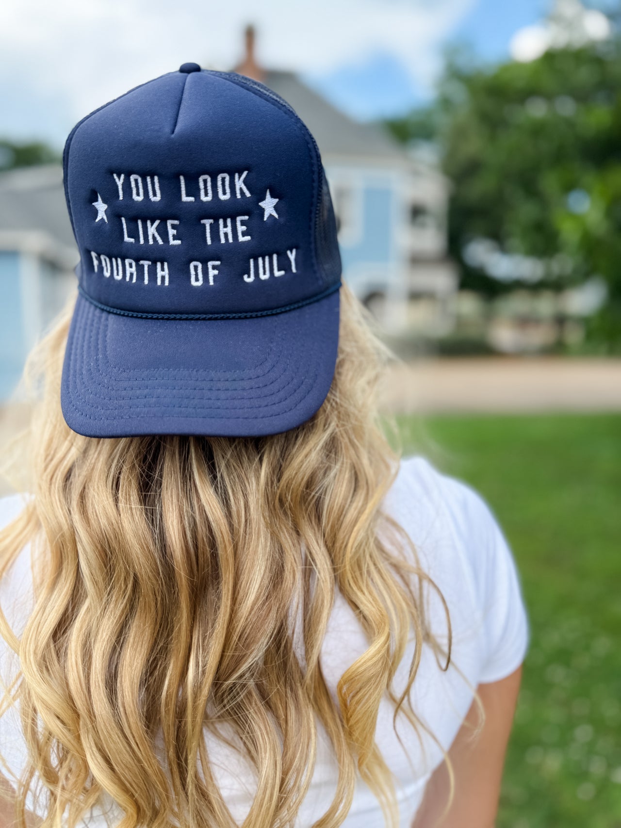 Person wearing a navy blue cap with text, outdoors on a sunny day.