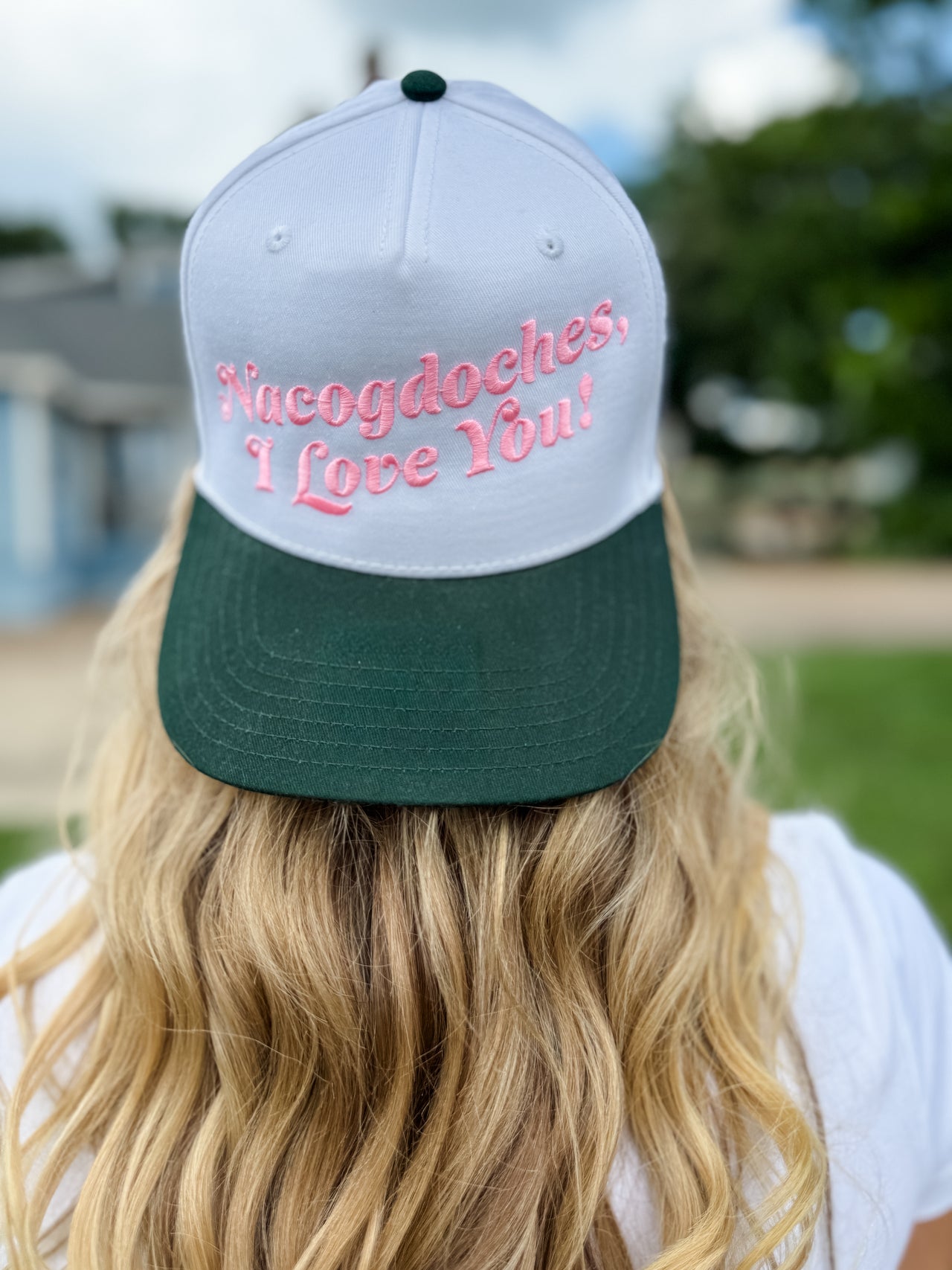 Person wearing a cap with 'Nucogdoches, Love You!' text outdoors