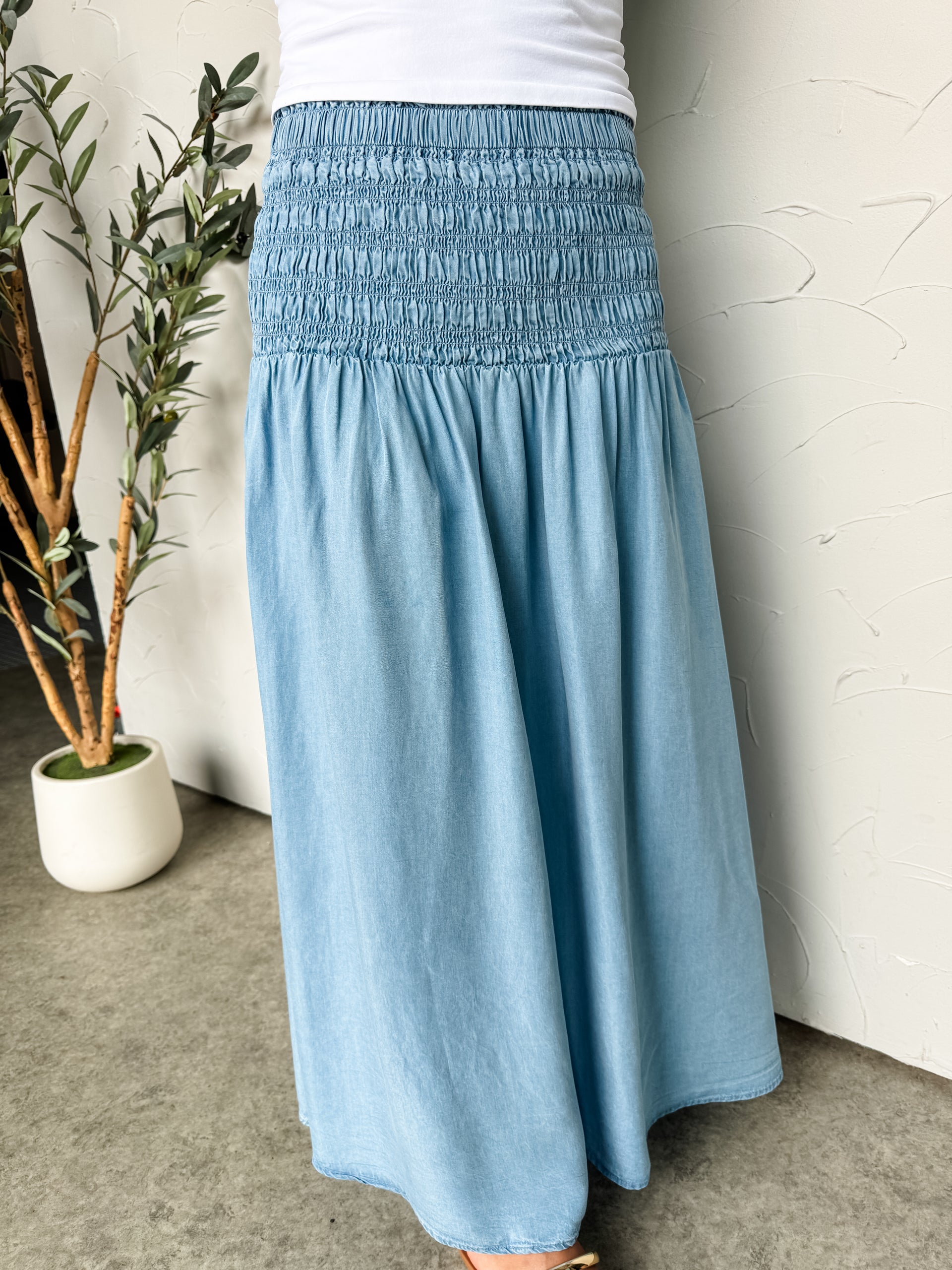 Light blue skirt worn by a person indoors with a plant in the background