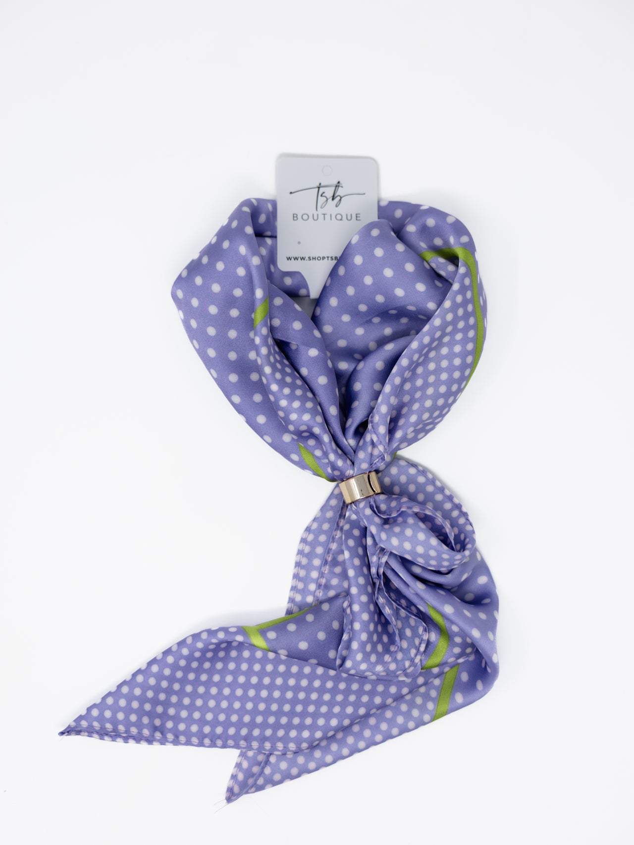 A lavender purple silk scarf with white polka dots and lime green geometric accents, tied with a small gold ring and attached to a white 'Tis a Boutique' tag, on a clean white background.