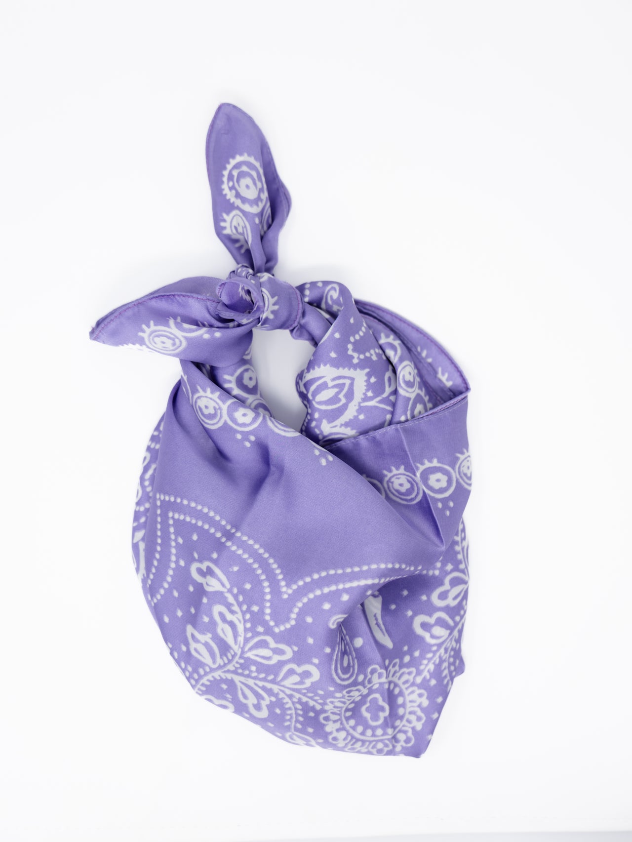 A purple bandana with a white paisley pattern, tied in a knot and displayed on a clean white background.