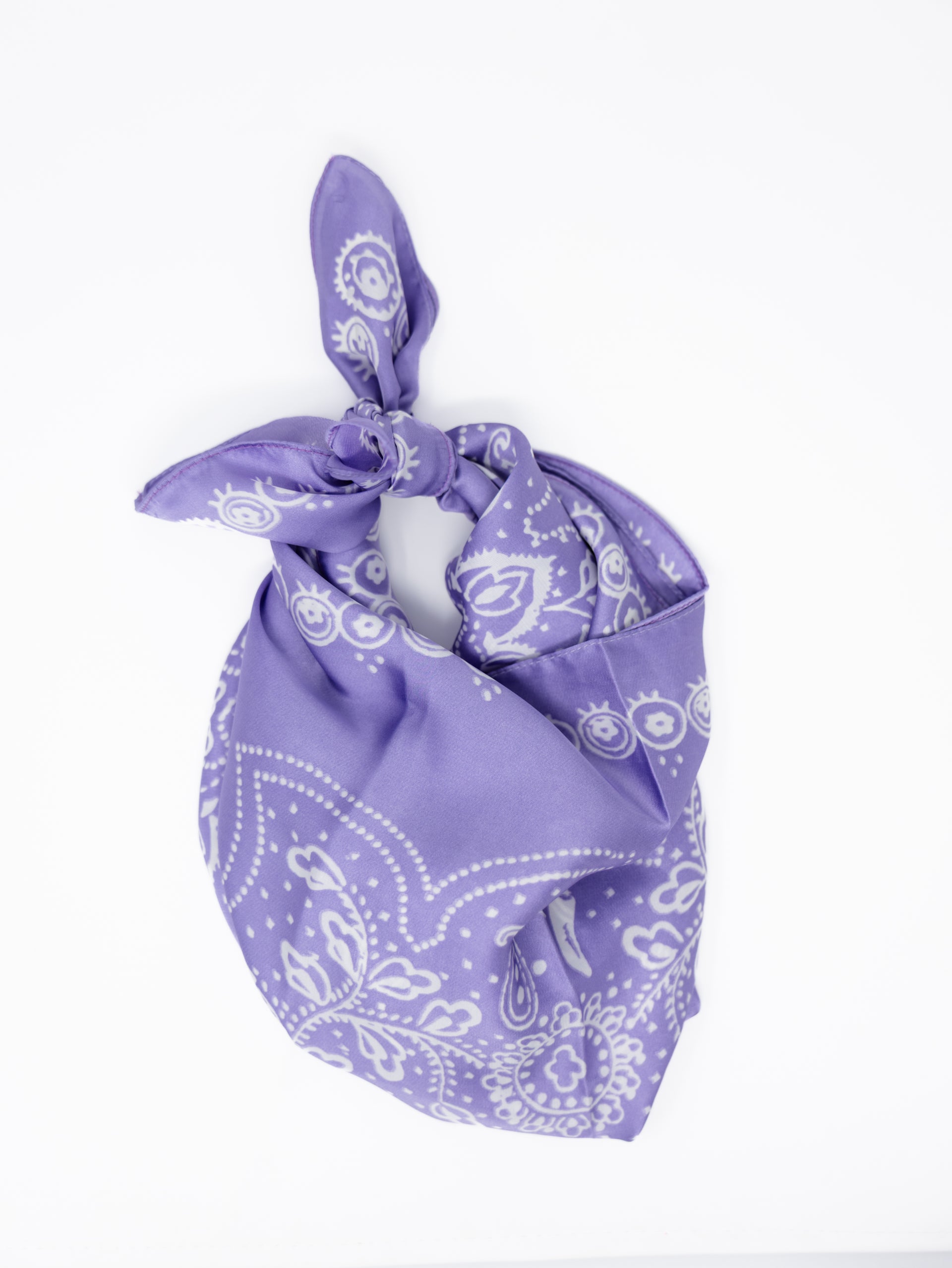 A purple bandana with a white paisley pattern, tied in a knot and displayed on a clean white background.