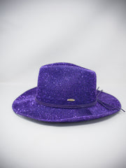 A purple glitter fedora hat with a matching purple band and a small gold emblem, photographed on a light gray background.
