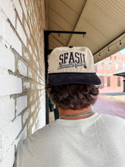 Person wearing a cap with 'SFASU Lumberjacks' text, standing against a brick wall.