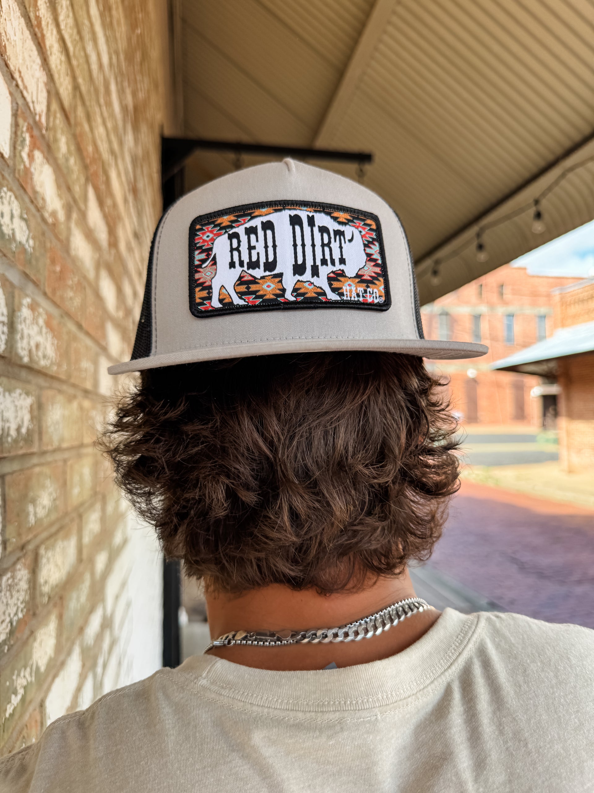 Person wearing a cap with 'Red Dirt' logo, standing in front of a brick wall.