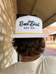 Person wearing a white cap with 'Red Dirt Hat Co.' logo, standing in front of a brick wall.