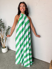 Woman wearing a green and white striped dress against a white wall.