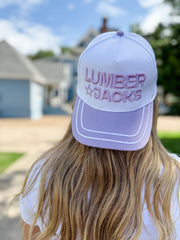 Person wearing a 'LUMBER JACKS' cap outdoors with a house in the background