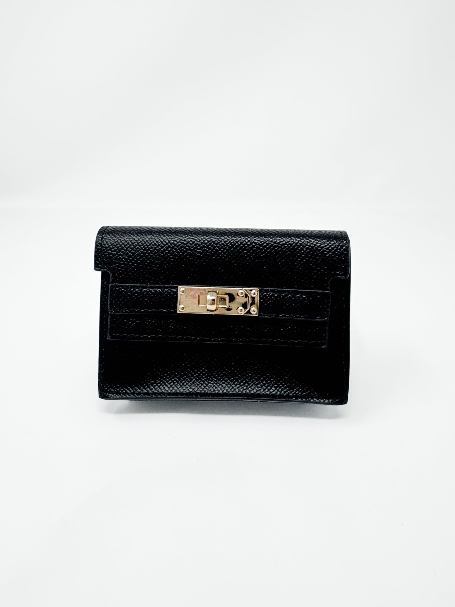 A small, structured black faux-leather wallet shown against a plain white background. The wallet features a fine textured, pebbled finish, a classic front flap design, and a polished gold rectangular turn-lock closure.