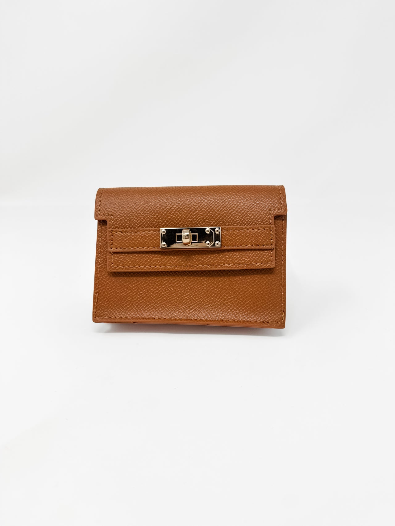 A small, structured camel-brown faux-leather wallet shown against a plain white background. The wallet features a fine textured, pebbled finish, a classic front flap design, and a polished gold rectangular turn-lock closure.