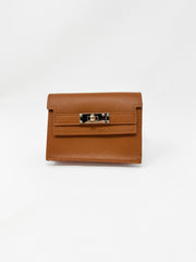 A small, structured camel-brown faux-leather wallet shown against a plain white background. The wallet features a fine textured, pebbled finish, a classic front flap design, and a polished gold rectangular turn-lock closure.