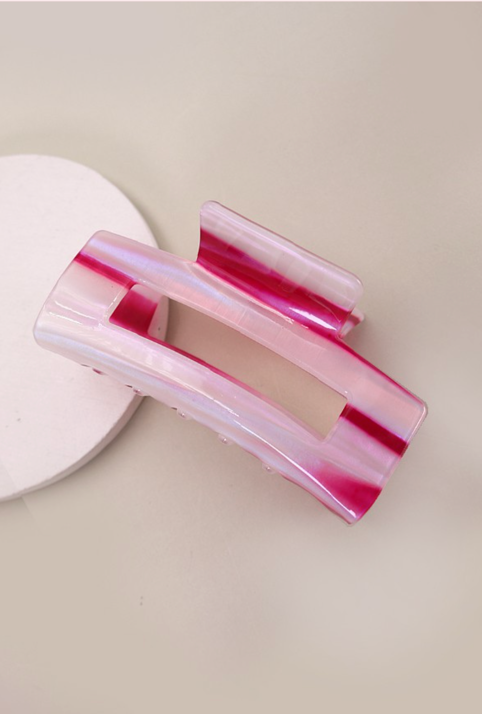 Pink and clear hair clip on a light beige background