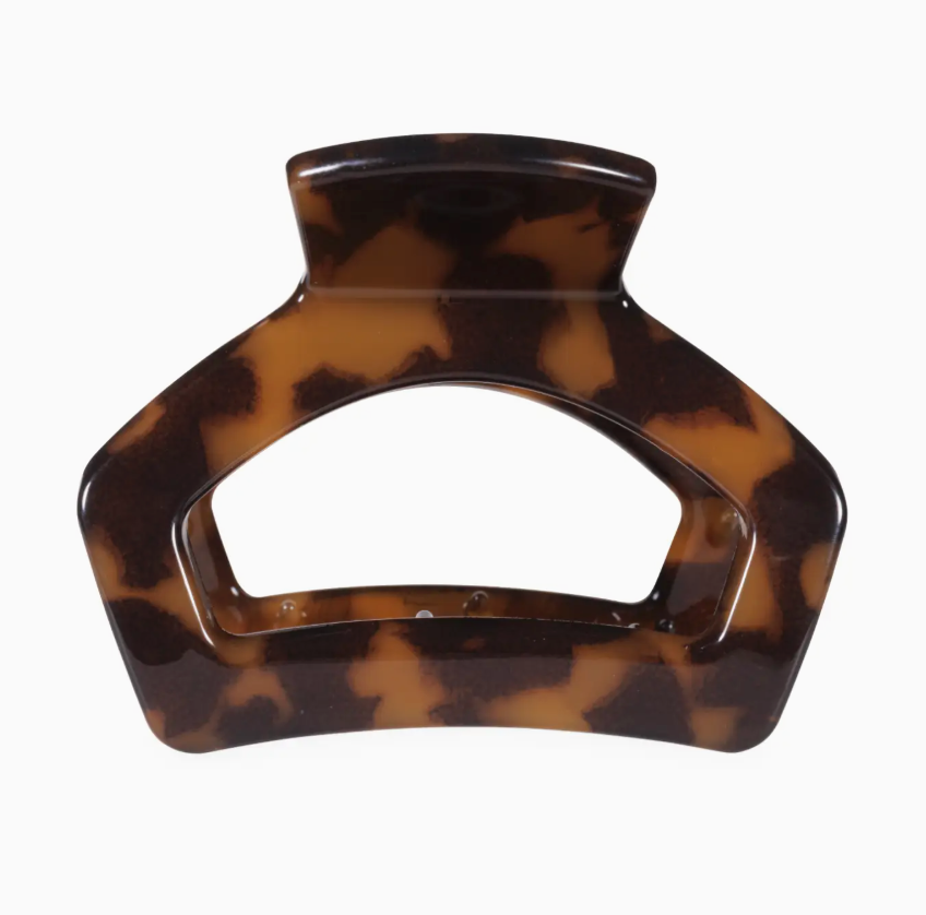 A tortoiseshell hair claw clip with a glossy finish, featuring a brown and amber pattern, shown against a plain white background.