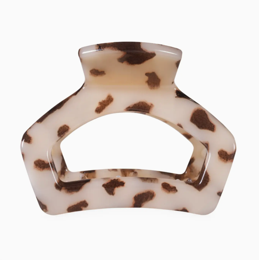 A tortoiseshell hair claw clip with a cream base and dark brown spots, shown against a plain white background.