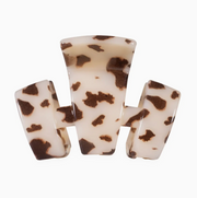 A three-prong hair claw clip made of glossy resin with a brown and cream tortoiseshell pattern, shown against a plain white background.