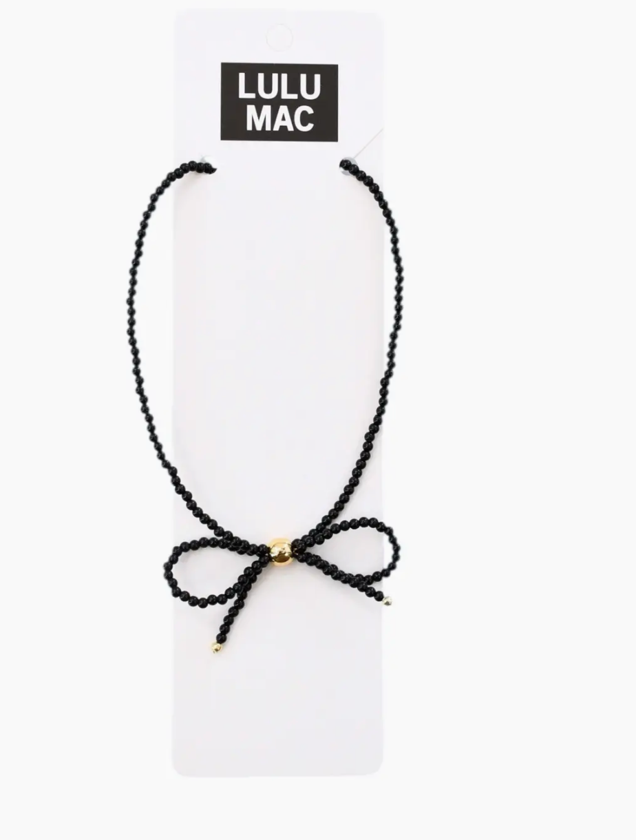 A black beaded cord necklace with a small gold bead accent at the center, displayed on a white card labeled 'LULU MAC' against a white background.