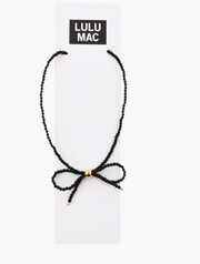 A black beaded cord necklace with a small gold bead accent at the center, displayed on a white card labeled 'LULU MAC' against a white background.