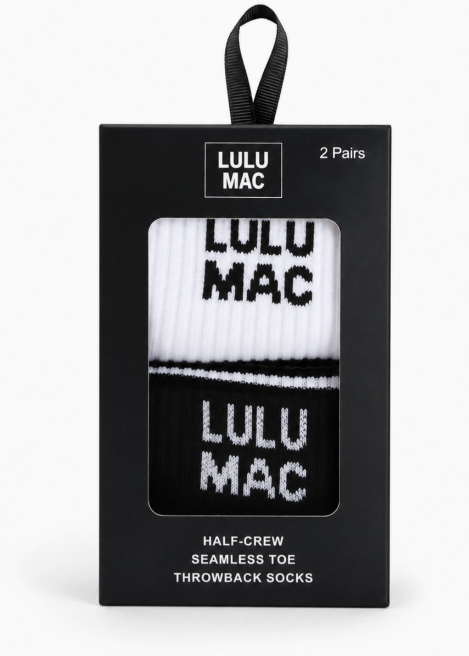 Lulu Mac half-crew seamless toe throwback socks in a black retail box. The socks are white and black with 'LULU MAC' text, shown through a clear window on the front of the packaging.